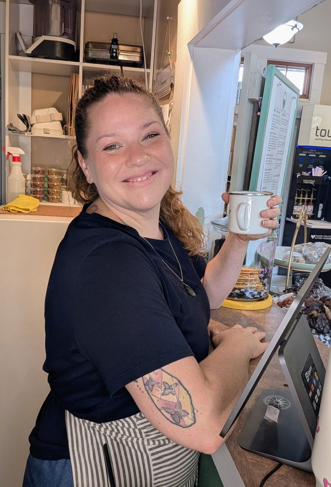 Chef Colleen at the counter smiling with a mug of chai