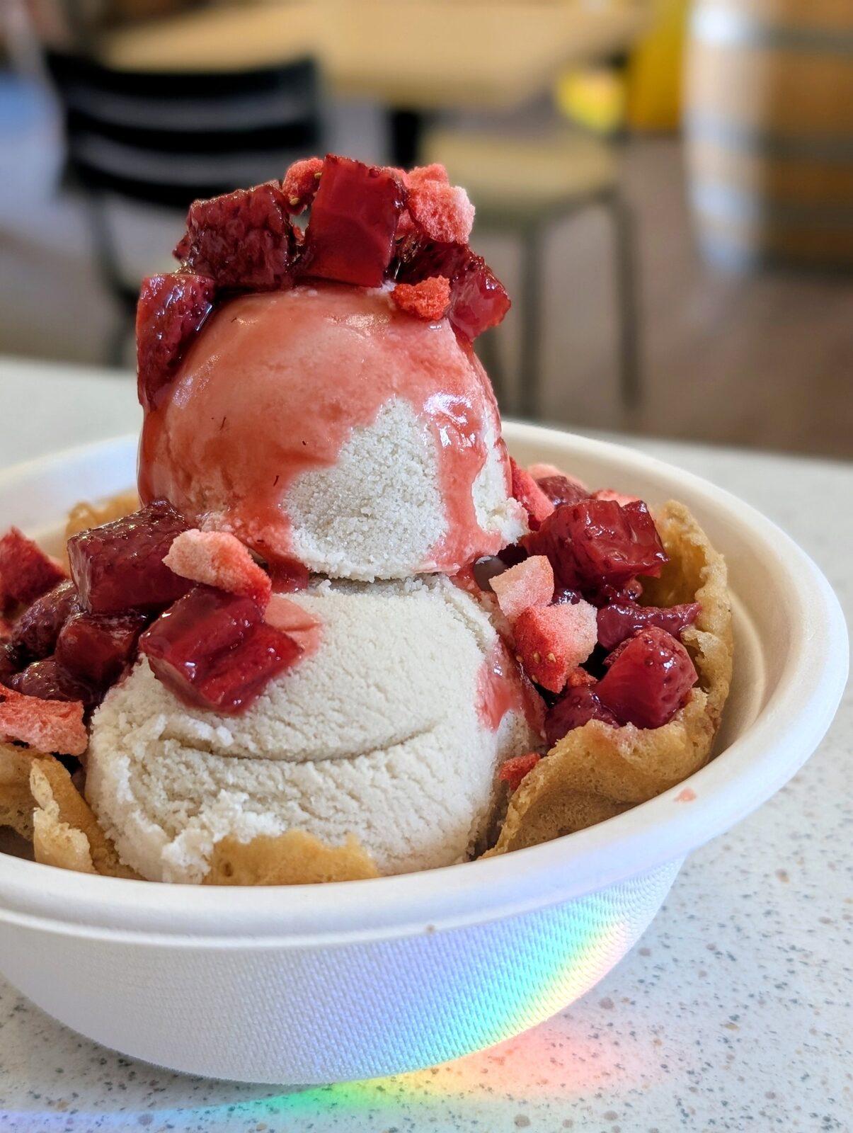 Scoops of ice cream over strawberries in a gluten-free waffle bowl