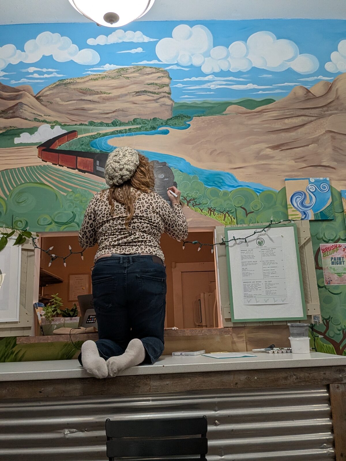 Chef Colleen painting the Okanagan landscape mural by hand