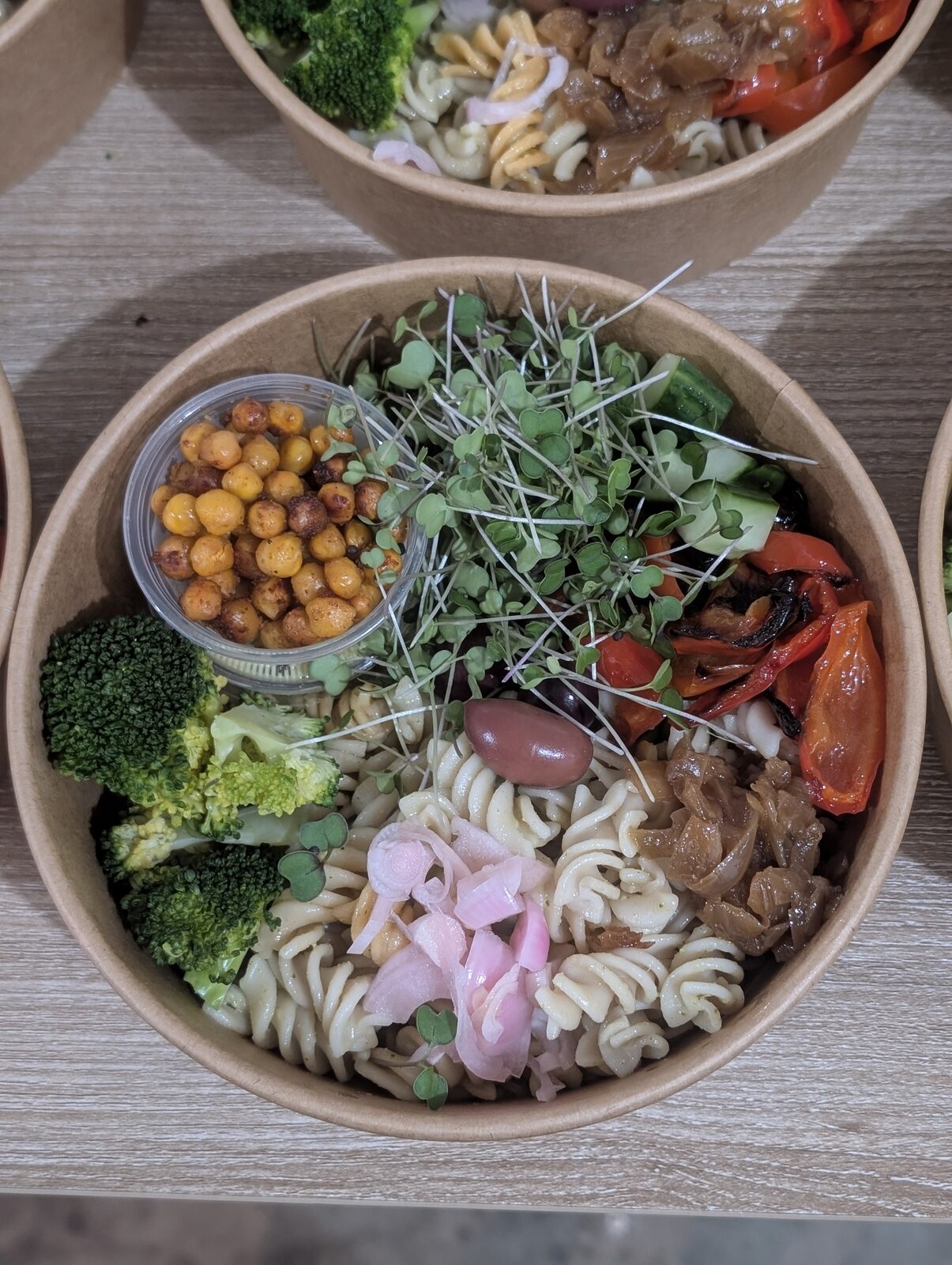 Pasta salad bowl with broccoli, roasted tomatoes, microgreens and chickpeas