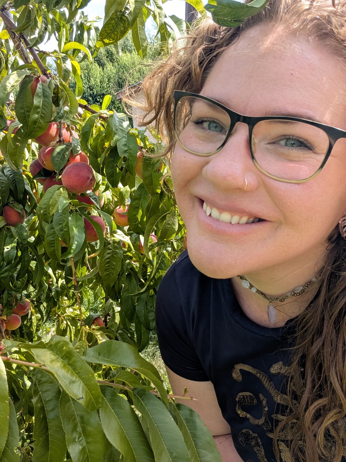 Chef Colleen smiling next to a peach tree in the Okanagan