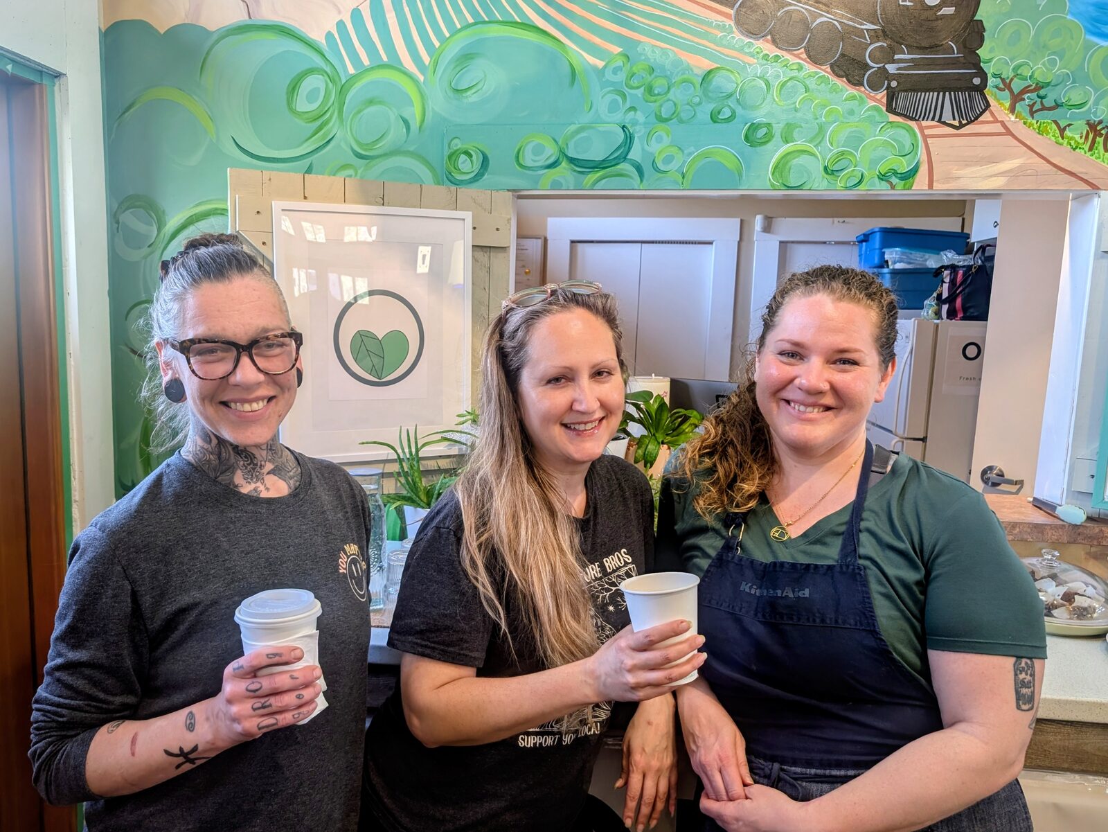 Chef Colleen with two friends in front of the OKGN To Go mural