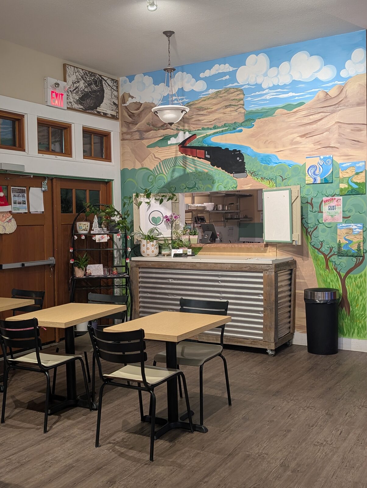 Inside OKGN To Go — hand-painted Okanagan mural above the counter with café tables and chairs